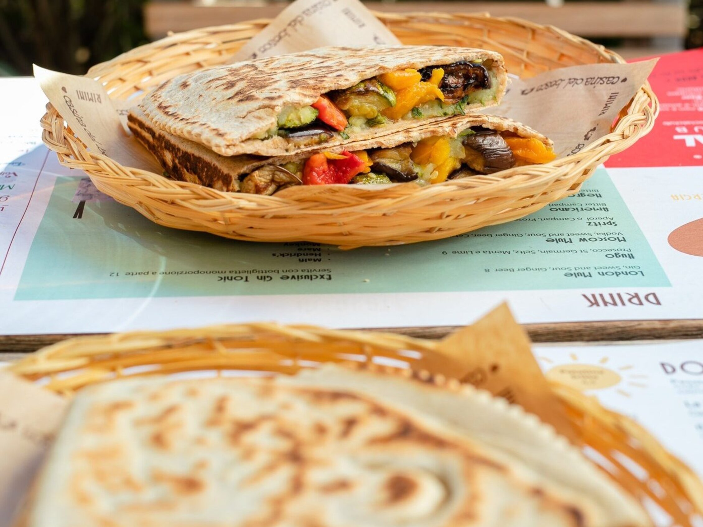 un tavolo con due piatti in vimini con all'interno delle appetitose piadine farcite