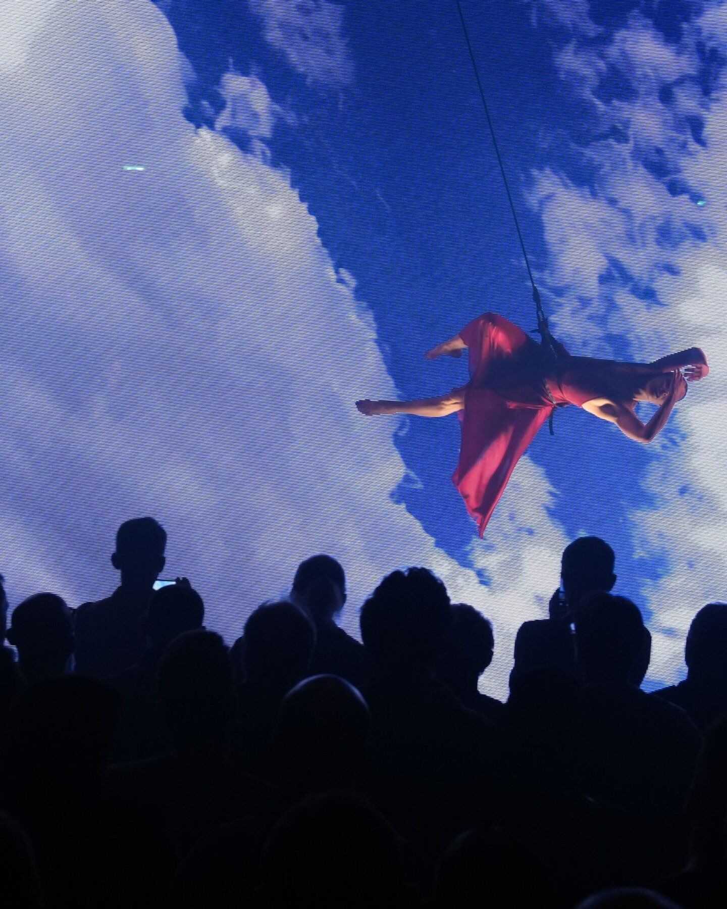 Performance aerea su sfondo digitale immersivo durante evento a MIR, pubblico in osservazione