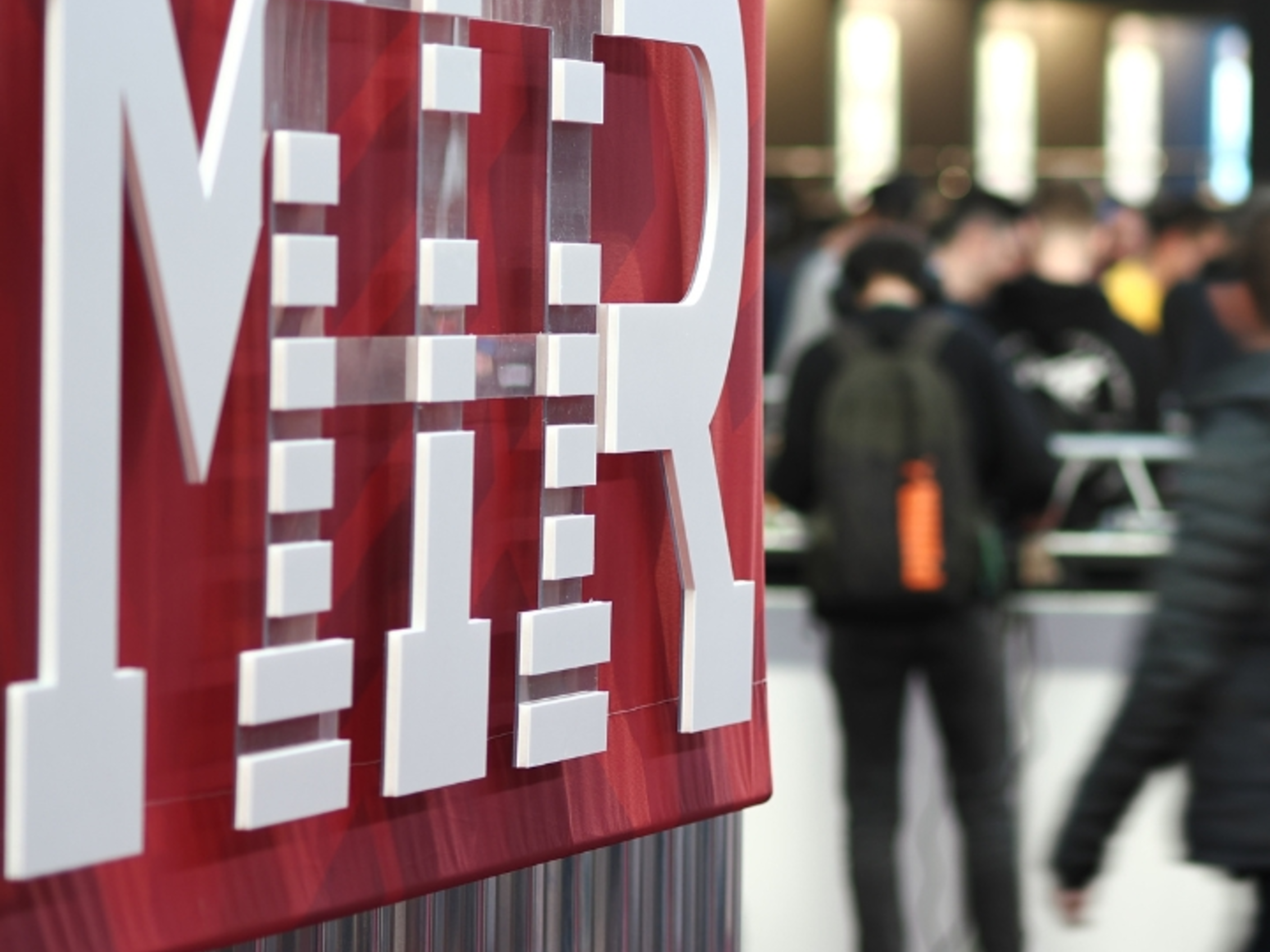 Logo MIR in fiera Dettaglio del logo MIR con visitatori in fiera sullo sfondo