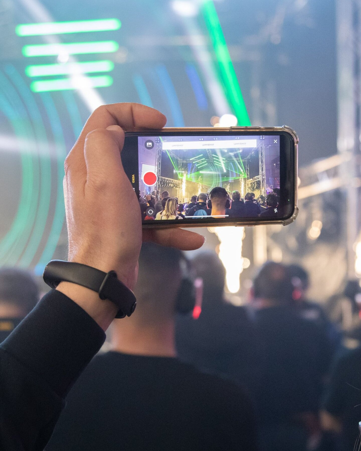 Persona che riprende uno show dal vivo con lo smartphone durante un evento musicale con luci e pubblico